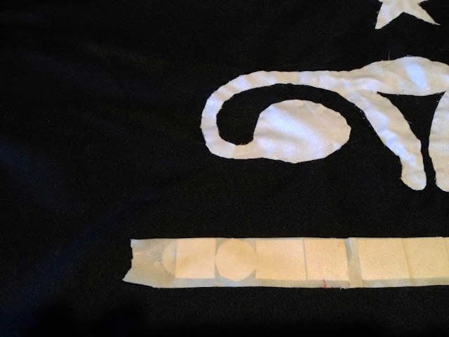 iron-on letters taped in place on a black flag