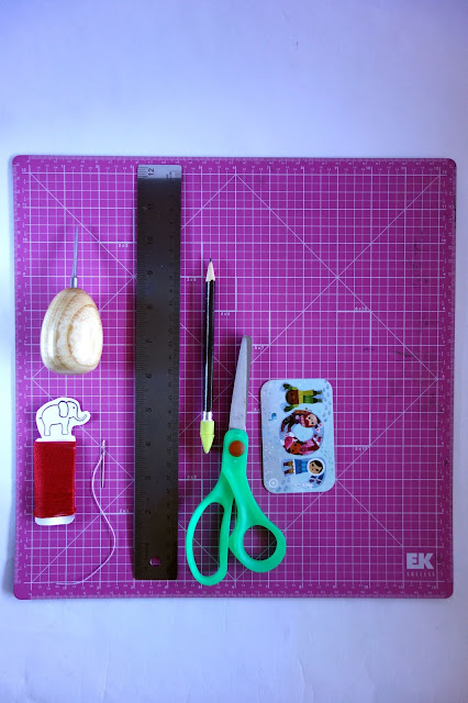 awl, needle and thread, self-healing mat, ruler, scissors, pencil, bone folder, craft materials