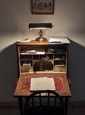 An artist's desk at night lit up by a desk lamp