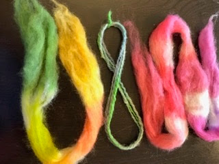 Green and yellow roving, blue and green yarn, and pink roving
