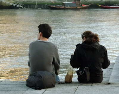 casal sentados na beira do rio comendo castanhas assadas