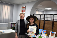 Zdjęcie przedstawia pracownika biblioteki wręczającego dyplom i nagrodę laureatowi Gminnego konkursu na strój bajkowy pt. „Bajkowy świat”.