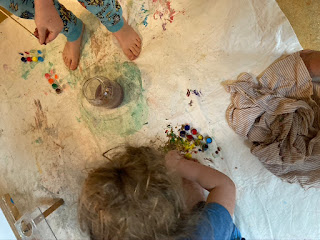 kids on the floor making art with paints on a splotched cloth