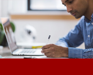 Man sitting in front of a laptop computer with pen