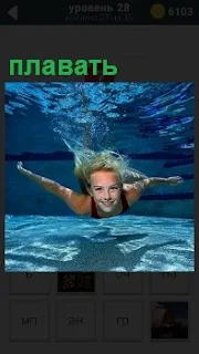 В бассейне под водой плавает девушка в купальнике, волосы в разные стороны, помогая себе руками