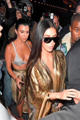 Kourtney Kardashian steps out in nothing but a sparkling bra and skirt while Kim coordinates in gold dress