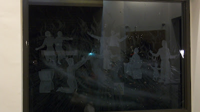 A picture of some people worshiping etched into the window above the church door.