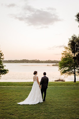 bride and groom holding hands looking out at the lake