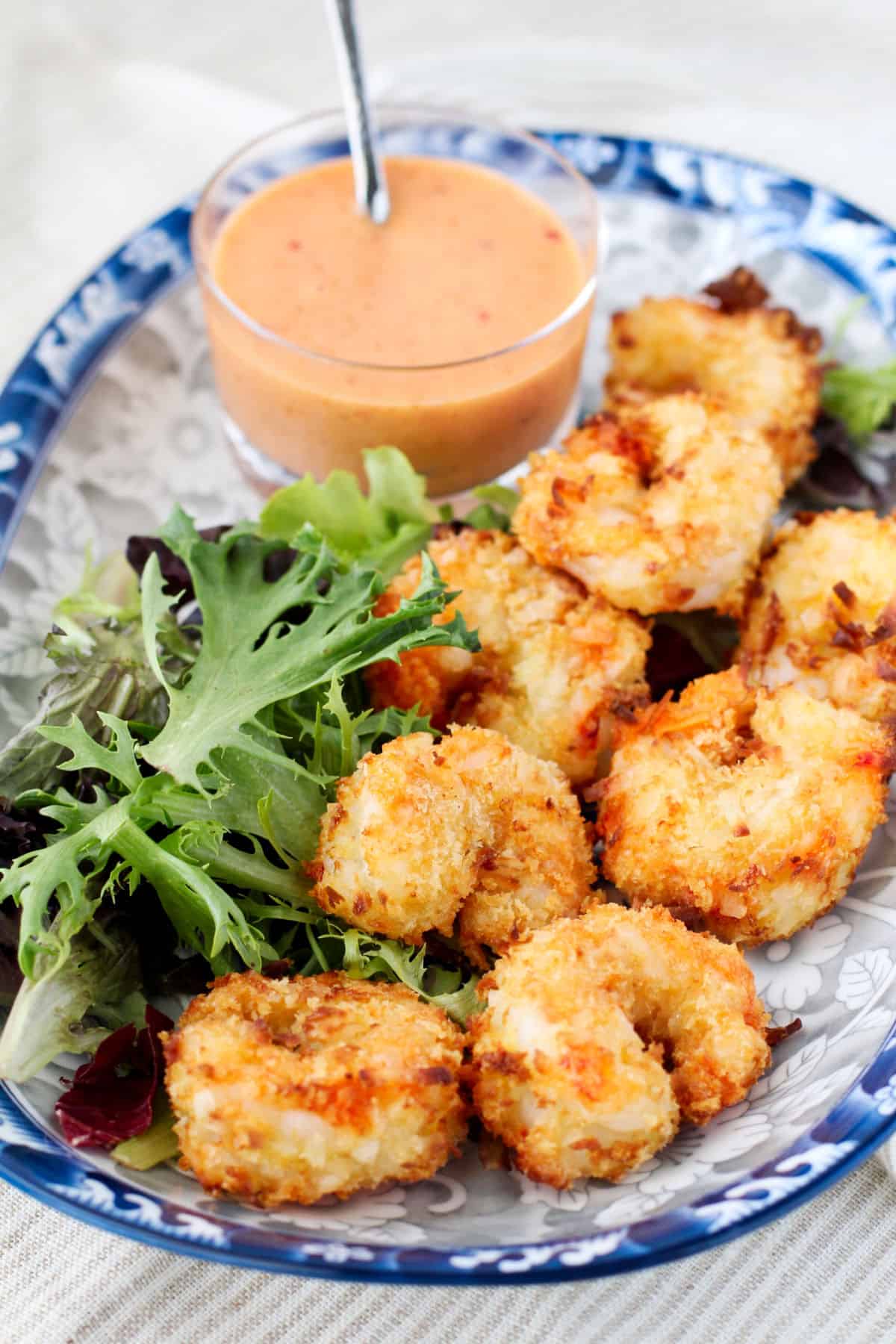 Air Fryer Crispy Coconut Shrimp on a plate with greens.