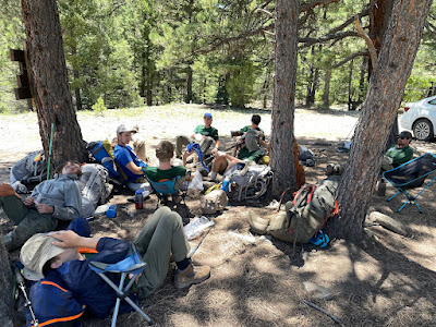 Group of boy scouts sitting as a group in camp chairs eating lunch