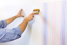 Pic of man's hands applying glue with brush for next sheet of wallpaper