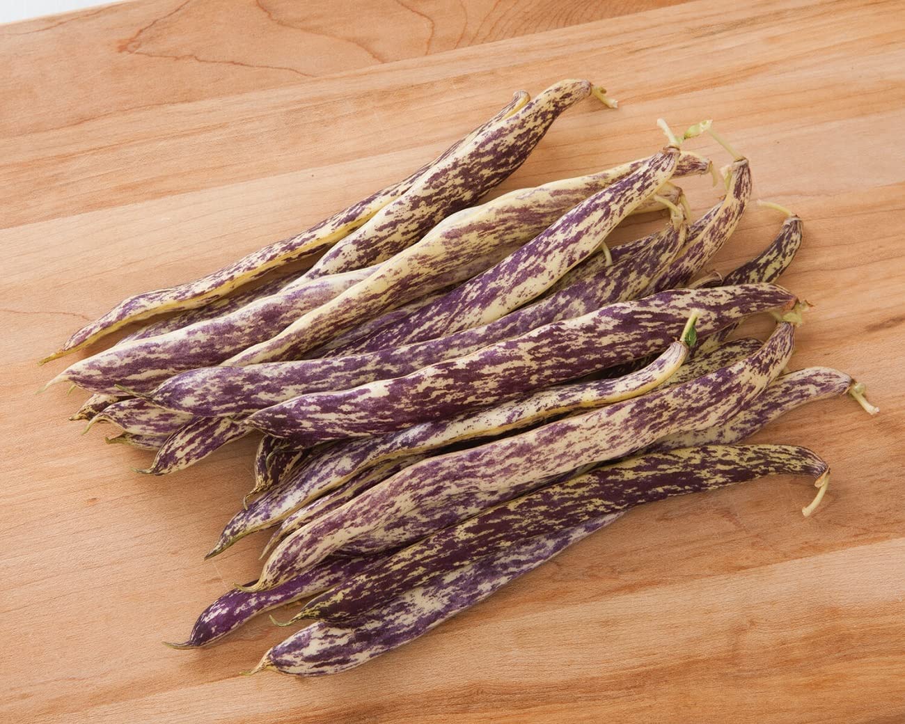 Unique flashy heirloom. Avg. 6–6 1/2" flat pods are pale yellow with purple streaks. They are tender and sweet and good in salads or cooked. Purple disappears upon cooking. Tan seeds with dark speckles.