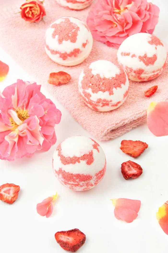 How to make a strawberry milkshake bath bomb without cornstarch. These cute and unique bath bombs would make a great gift. These natural bath bombs are fizzy and moisturizing. This DIY easy recipes uses essential oils for natural scents.  Home made pretty and cool bath bombs.  If you need ideas for summer bath bombs, try this recipe.  #bathbomb #diy #strawberry