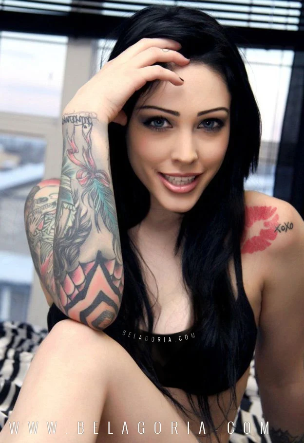 Bellisima mujer de mirada azul con tatuajes en brazos, lleva un tatuaje de labios rojos en el hombro