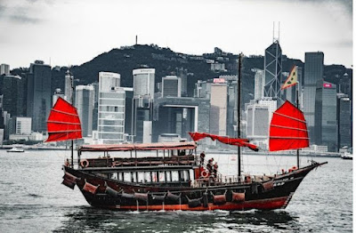 red and black boat with Hong Kong in the background