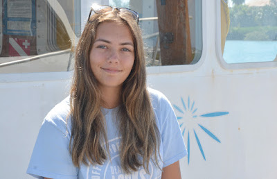 Ocean Academy intern Megan Zimmerer sitting in front of Bermuda Institute of Ocean Sciences boats.