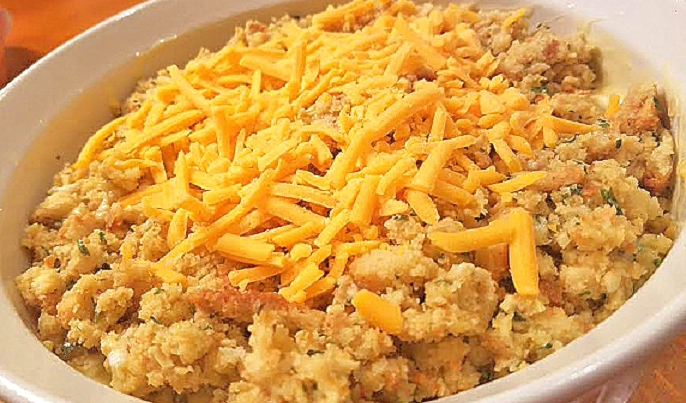 this is a cheddar cheese topped broccoli casserole in a large white revol baking dish