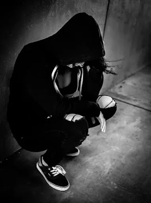 An image of a girl in black hoodie and sneakers.