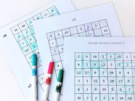 na zdjęciu trzy karty pracy z tabelkami służącymi do gry i znajdywania ukrytych w nich działań, na planszach leża trzy mazaki w kolorach niebieskim, różowym i zielonym