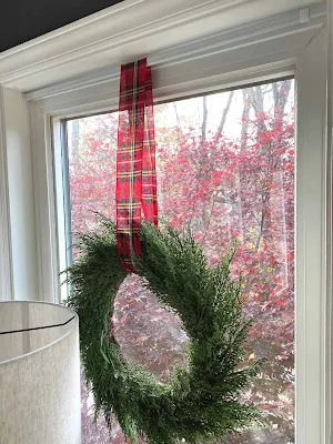wreath hanging from ribbon held by tension rod in interior window