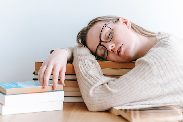 Tired woman sleeping on pile of books