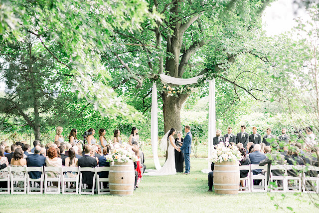 Niagara Wedding Planner | A Divine Affair | Sara and Daniel - Photo by Julia Park Photography. Ceremony and Reception at Kurtz Orchards Gracewood Estates. Ceremony under a chiffon and floral draped tree. Reception in a tent with live edge wooden harvest tables. 