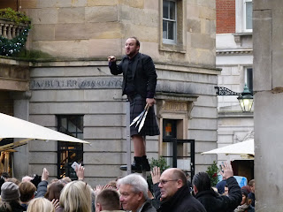 A street entertainer wearing a kilt balancing on top of a ladder while juggling knives, Covent Garden, London