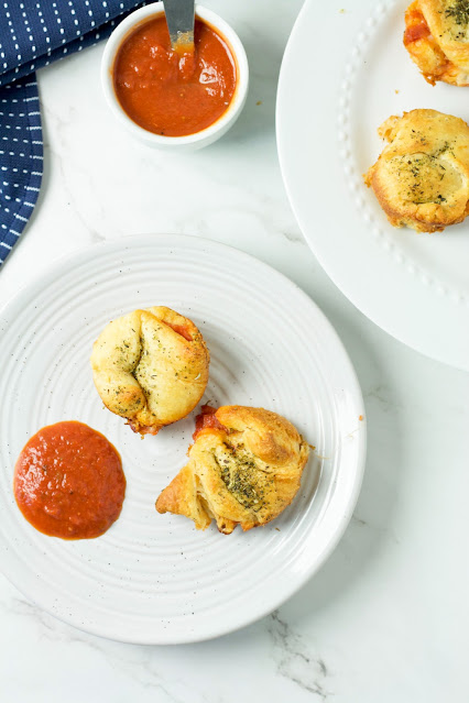 pizza bites and pizza sauce on a white plate.