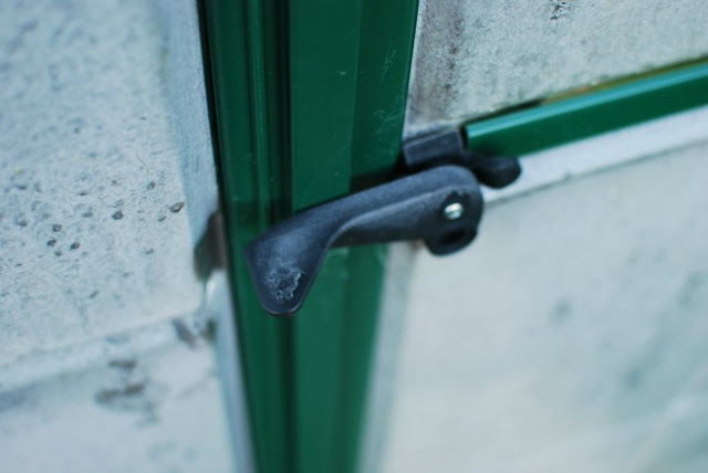 Door handle and glass of greenhouse covered in ice.