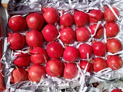 A close-up of a variety of pomegranates, highlighting their rich red color and plump, juicy appearance.