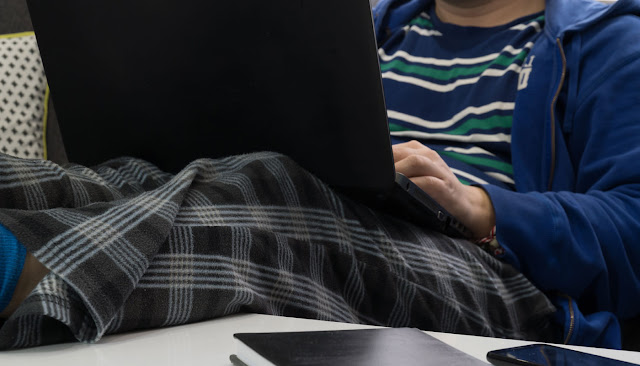 Homem sentado de pijama em seu notebook