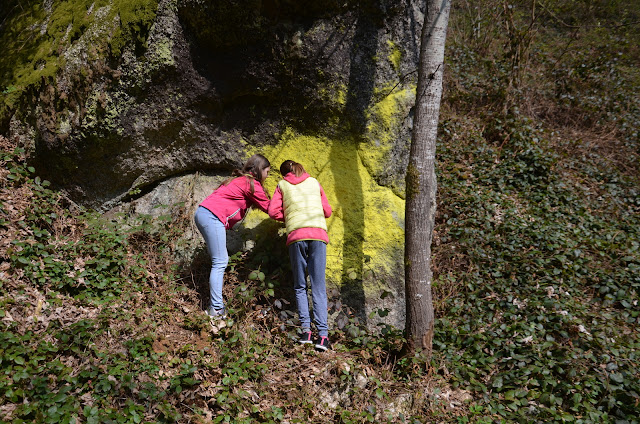 Zwei Mädchen vor einem großen Granitstein mit gelben Flechten.