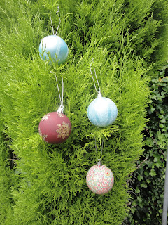 Four decorated baubles in a fir tree