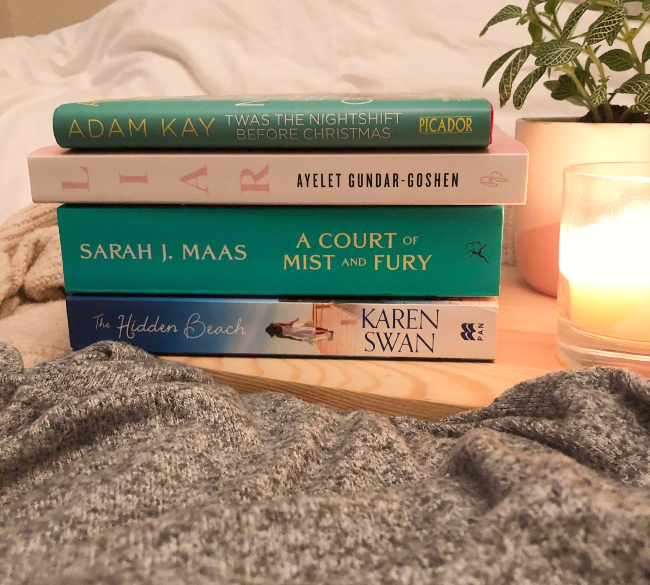 Stack of blue, green and pale pink books on a wooden board