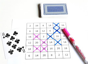 na zdjęciu wydrukowana plansza do gry z mnożeniem przez dwa, po lewej stronie leży karta osiem pik, po prawej stronie różowy pisak a nad planszą leży stos zakrytych kart