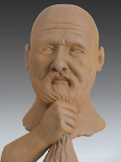 Figurative sculpture by sculptor Dan Woodard of a man holding his beard.  Sculpture made of clay with a rusted iron coating.