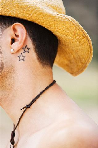 Black and white photo of a man's calf with simple star tattoo