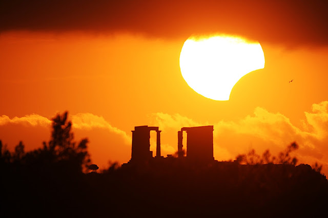 Eclipse over the Temple of Poseidon What's happened to the Sun? The Moon moved to partly block the Sun for a few minutes in January 2010 as a partial solar eclipse became momentarily visible across part of planet Earth. In this single exposure image, meticulous planning enabled careful photographers to capture the partially eclipsed Sun well posed just above the ancient ruins of the Temple of Poseidon in Sounio, Greece. Unexpectedly, clouds covered the top of the Sun, while a flying bird was caught in flight just to the right of the eclipse. At its fullest extent from some locations, the Moon was seen to cover the entire middle of the Sun, leaving the surrounding ring of fire of an annular solar eclipse.  Image Credit & Copyright: Chris Kotsiopoulos & Anthony Ayiomamitis Explanation from: http://apod.nasa.gov/apod/ap100118.html
