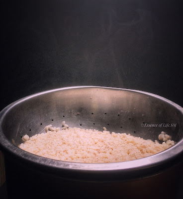 Steaming hot cooked Kerala Matta rice in a colander after draining.