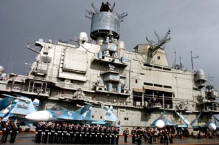 epa03053687 A handout photo released by the official Syrian Arab News Agency (SANA) showing crew lined up aboard Russian aircraft carrier Kuznetsov in the sea port city of Tartous in Syria on 08 January 2012. A Russian flotilla has docked at the Syrian port of Tartus in a show of solidarity with the regime of President Bashar al-Assad, Syrian state media reported. The flotilla is to stay for six days at the port, according to the report.  EPA/SANA