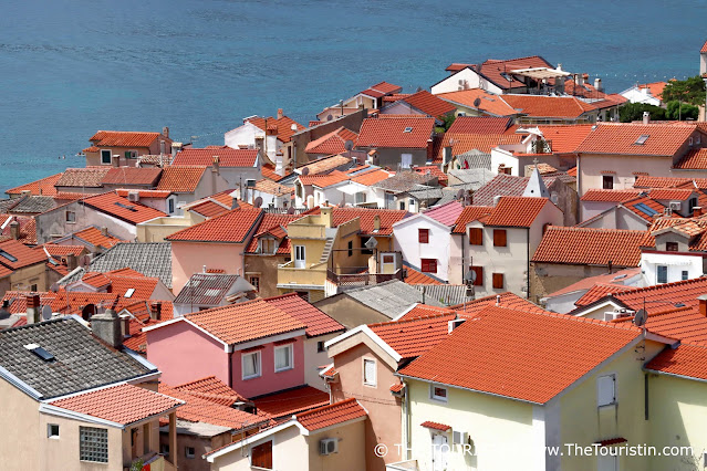 Red rooftops of a maze of colourful houses by the sea.