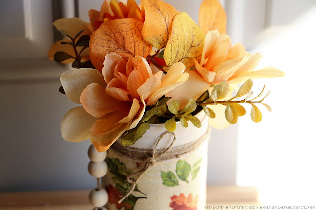 Close-up of faux floral, metal can, and wooden beads