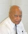 Headshot of a bald, middle-aged Black man wearing a white shirt and black necktie