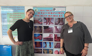 Medical mission nursing staff in front of a poster commemorating IEP's 25 years of service to the people of Can Tho.