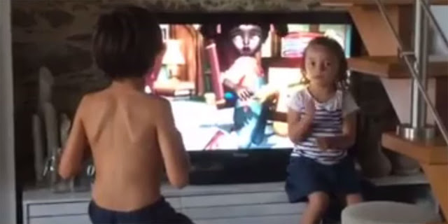 Niña interpretando de televisión a a lengua de signos a su hermano sordo