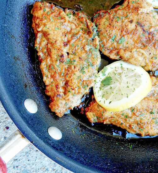 Lemon Butter Chicken garnished with lemon slices and fresh parsley in a skillet.