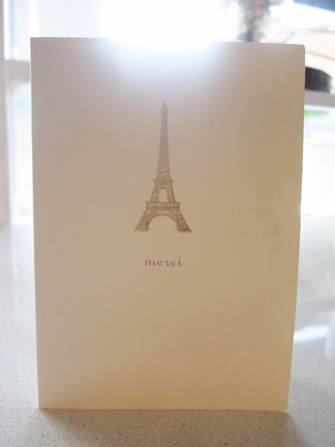 Cream colored card with the  Eiffel Tower and "Merci" written below it