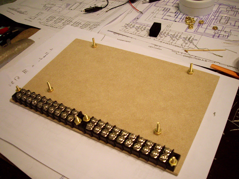 Terminal strips and brass support bolts fastened to a hardboard base