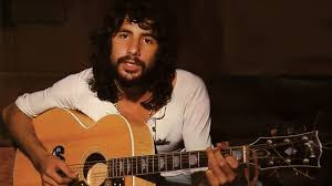 foto de Cat Stevens tocando violão ainda novo de cabelos pretos e longos