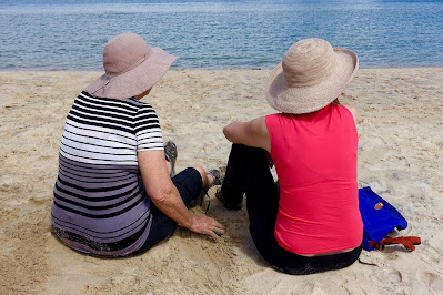 two women sitting on the beach